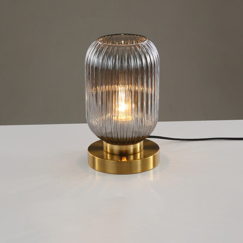 Table lamp with ribbed glass shade and brass base on a white surface with gray background