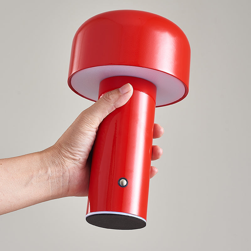 Red handheld lamp held by a hand against a gray background