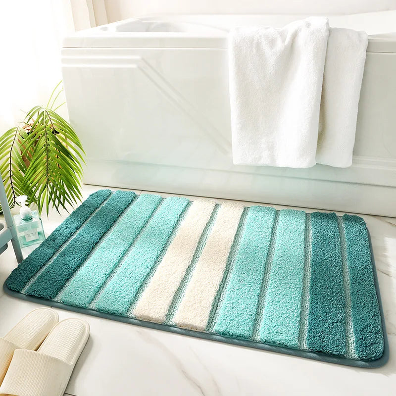 Striped bath mat with blue and green gradient on a bathroom floor.