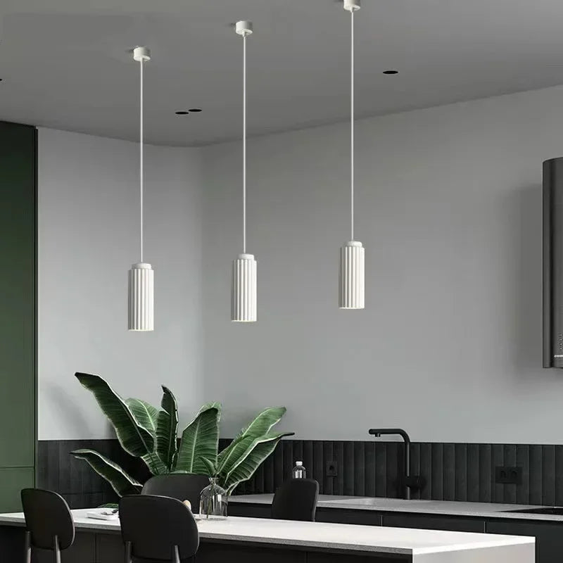 Modern kitchen interior with pendant lights, a plant, and a white countertop.