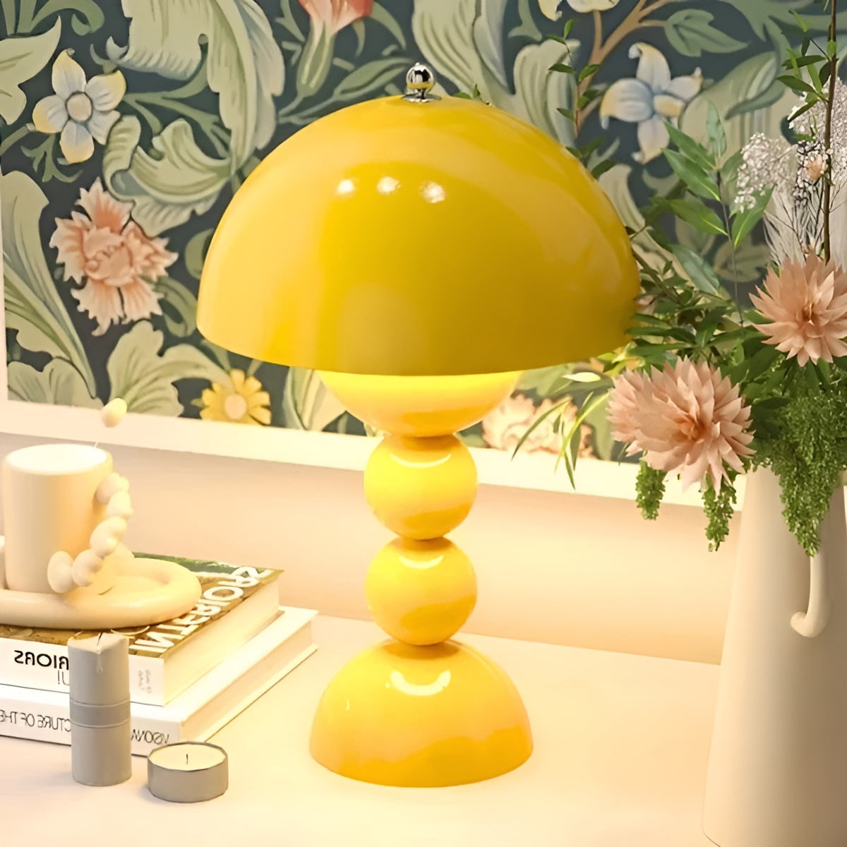 Yellow table lamp on a desk with floral wallpaper in the background