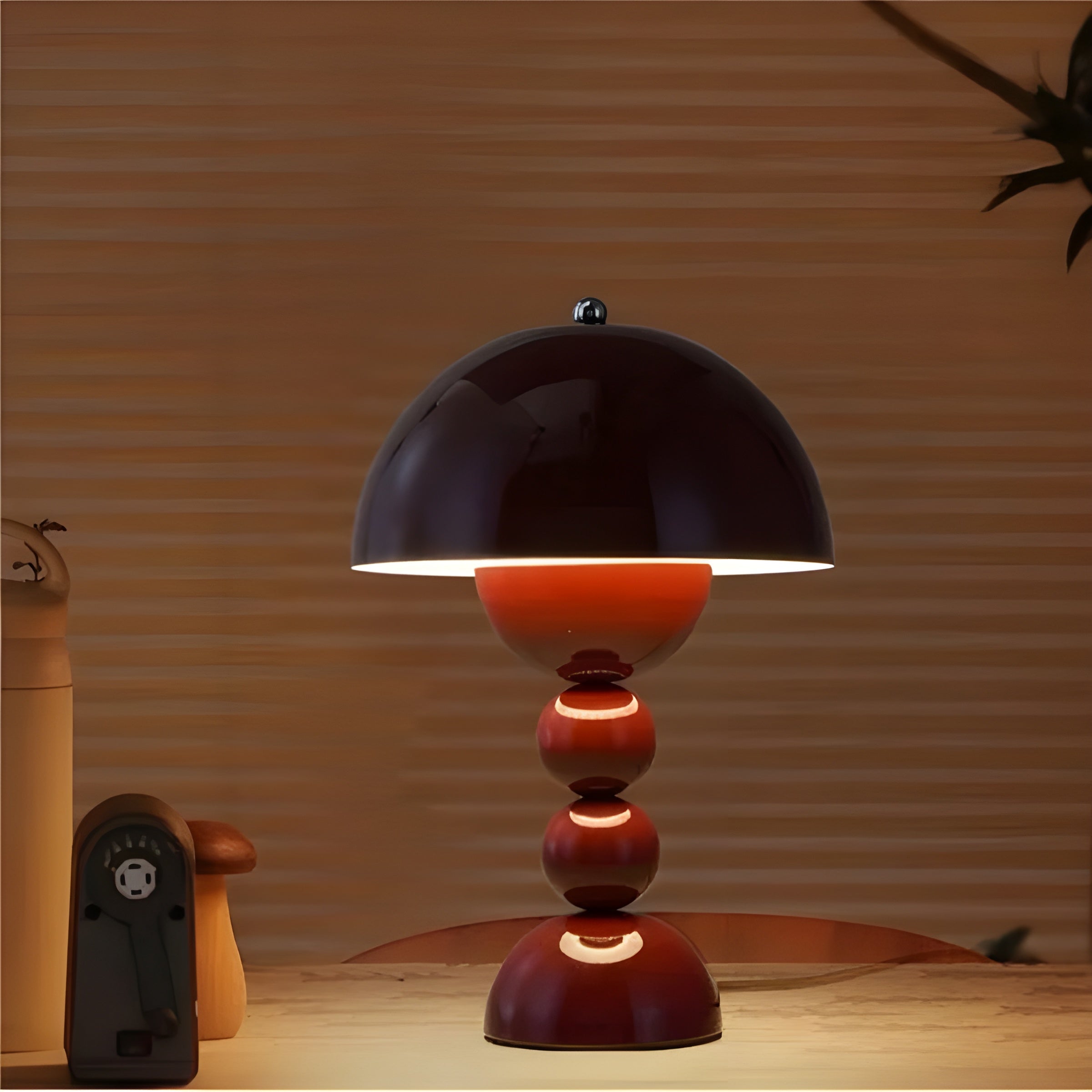 Table lamp with a black dome shade and red base on a wooden surface.