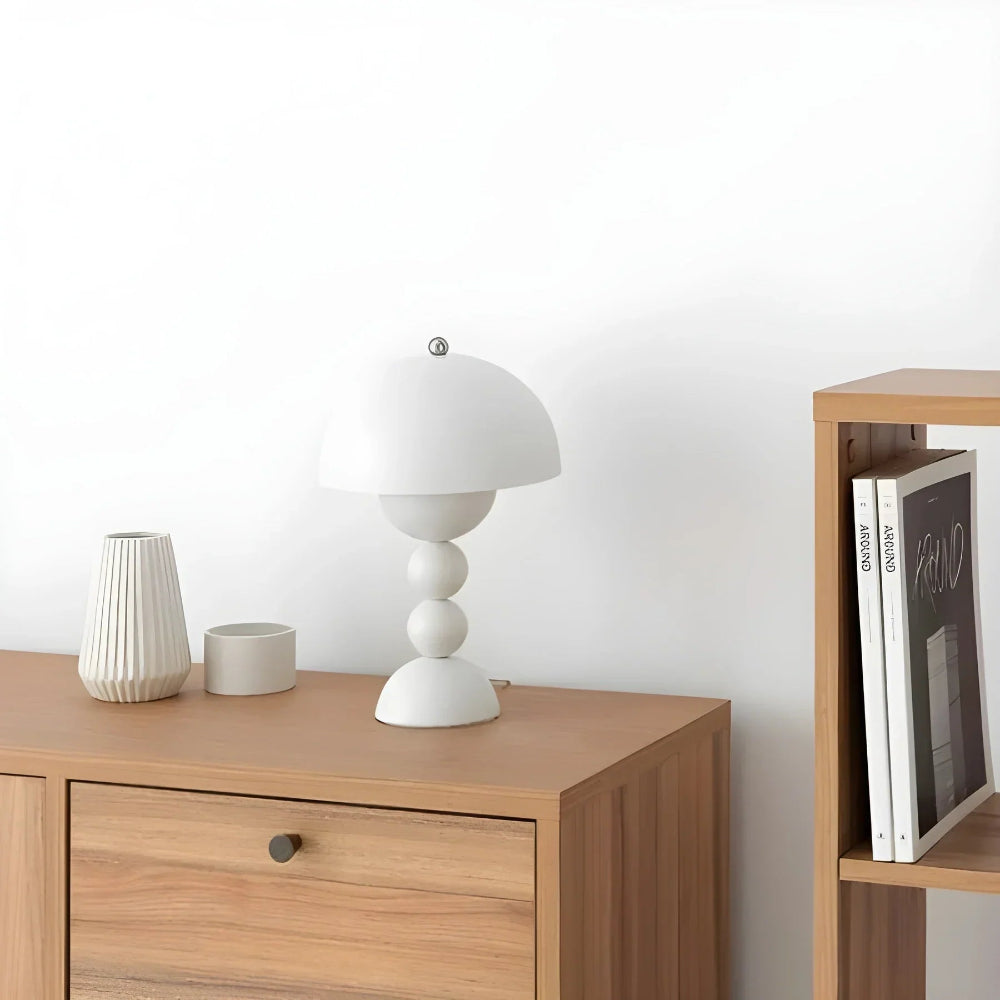 Wooden side table with a white lamp and decorative items, next to a bookshelf with books and a photo frame.