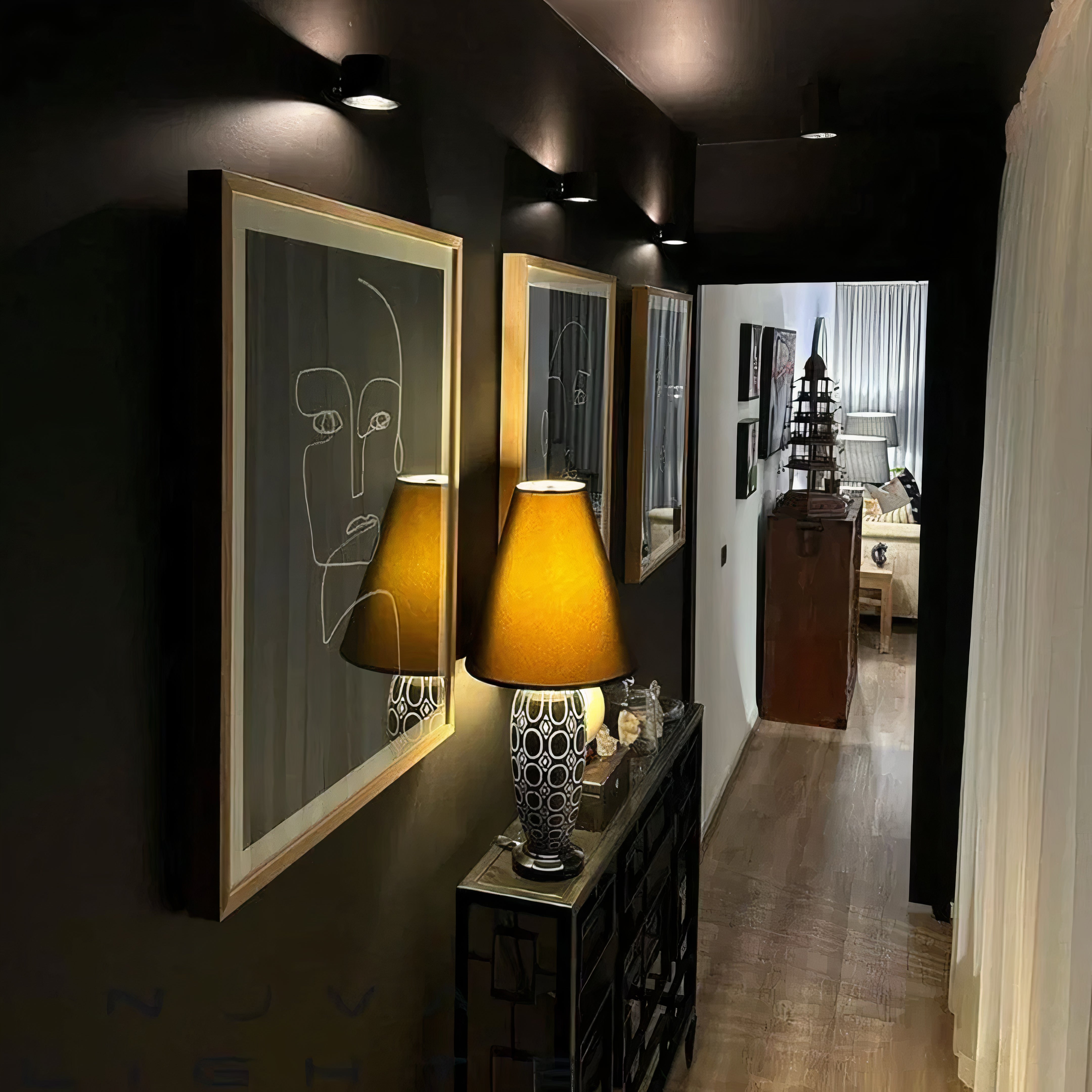 Modern interior with framed artwork and a lamp on a dark wall.