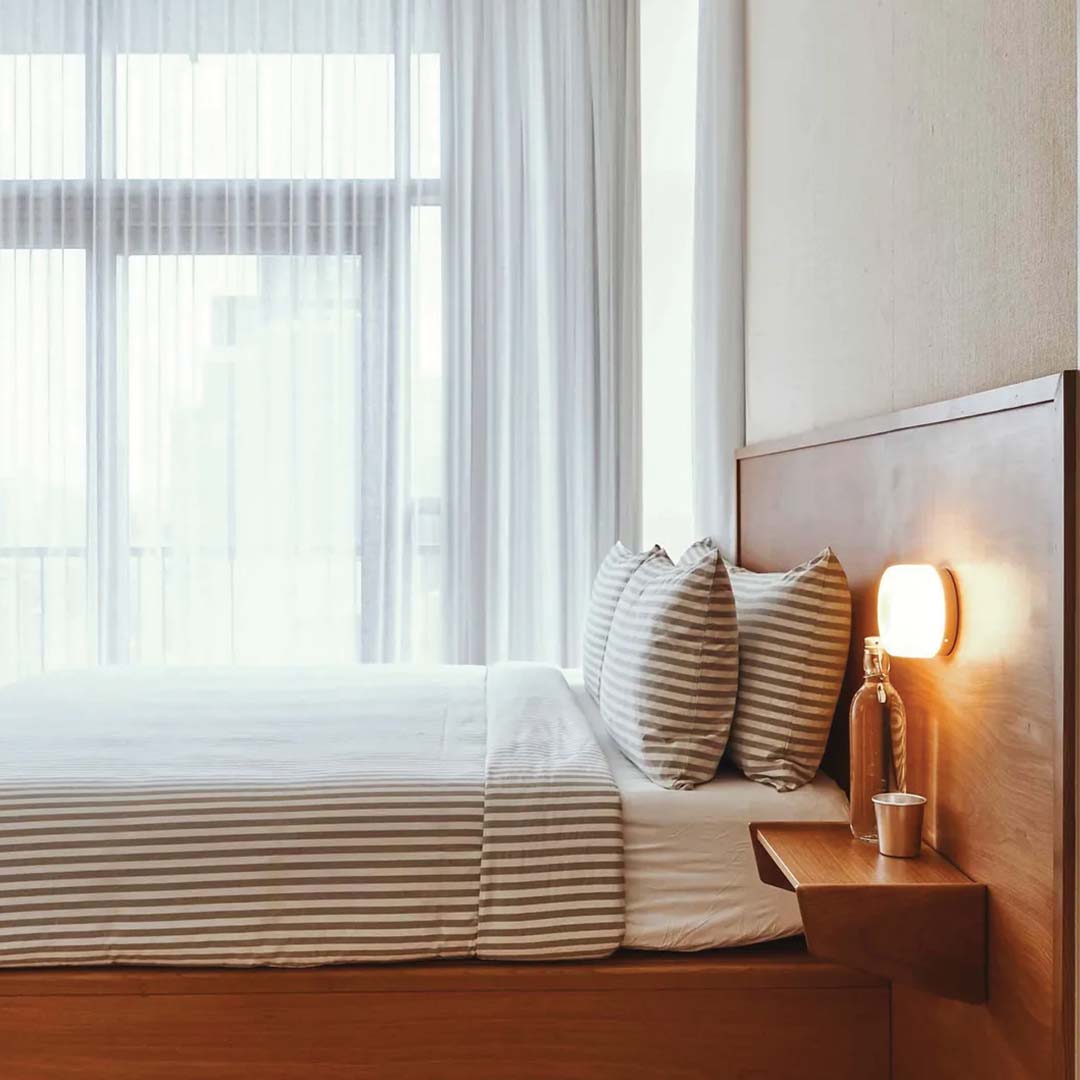 Bedroom with wooden bed, striped bedding, and nightstand with lamp.