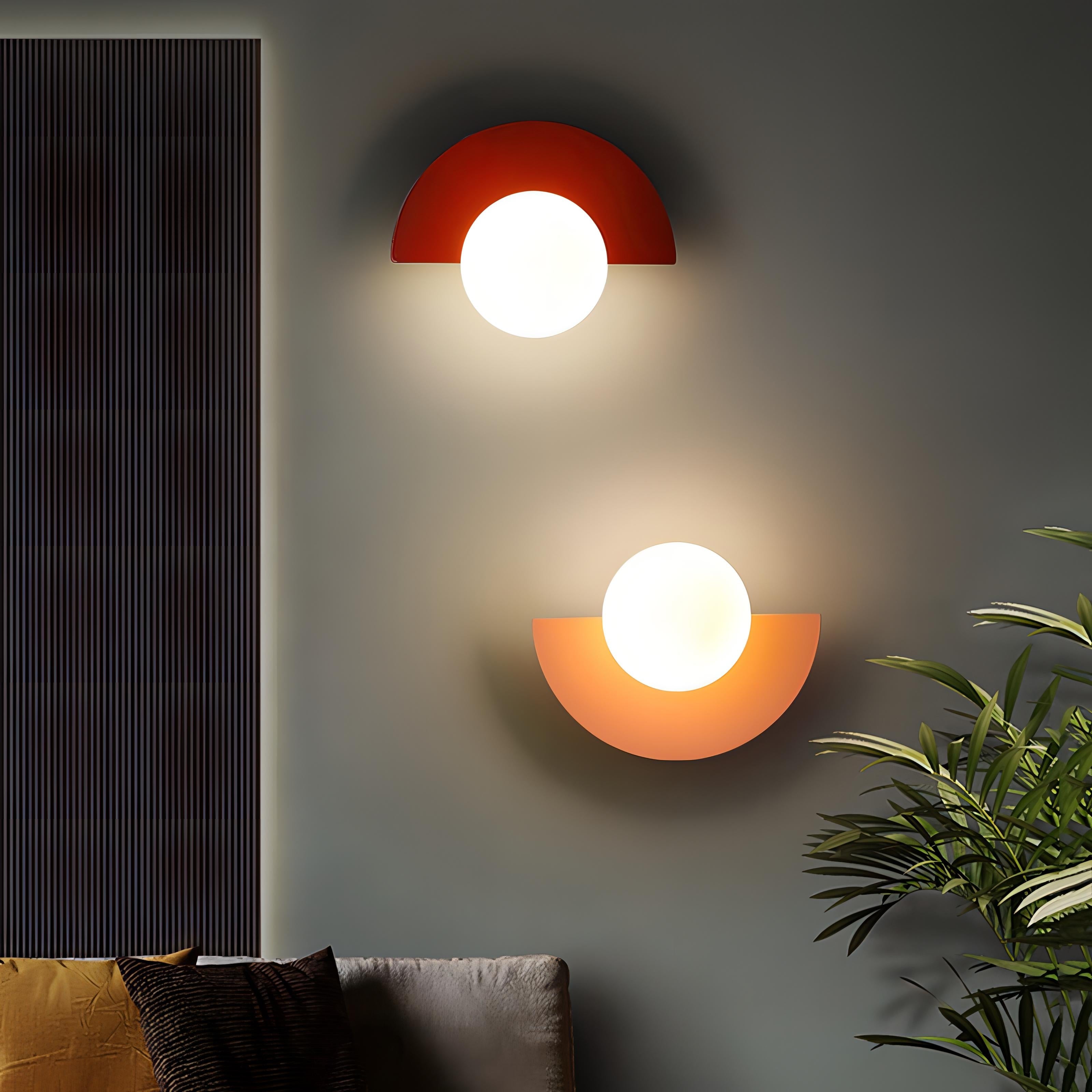 Two modern wall lights on a gray wall with a plant and sofa in the foreground.
