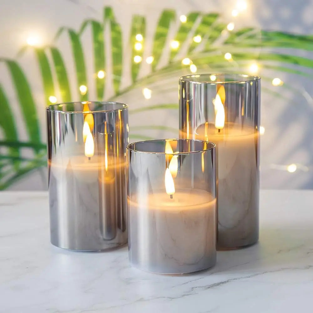 Three candles in metallic holders on a marble surface with a decorative background.