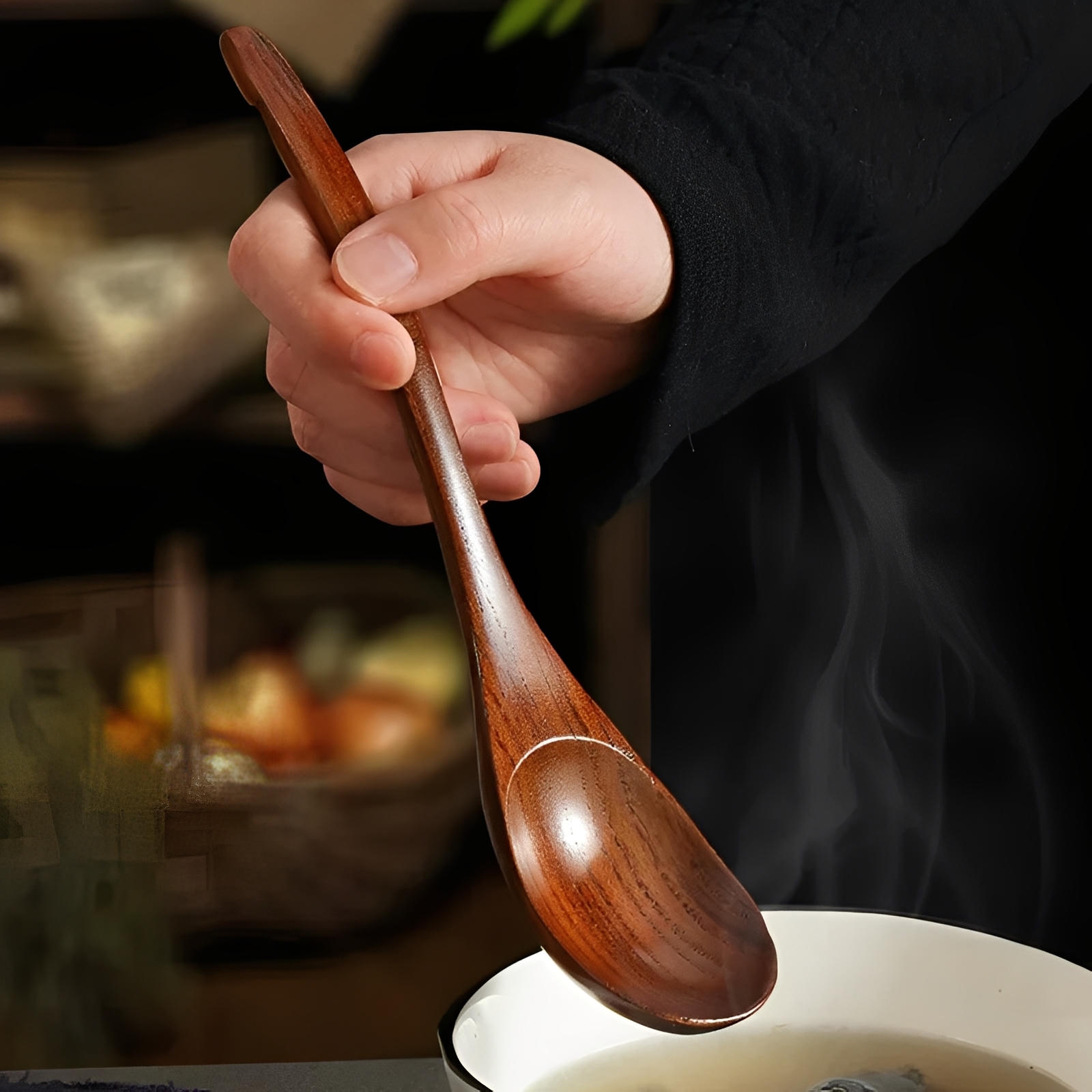 Hand holding a wooden spoon over a bowl with a blurred background