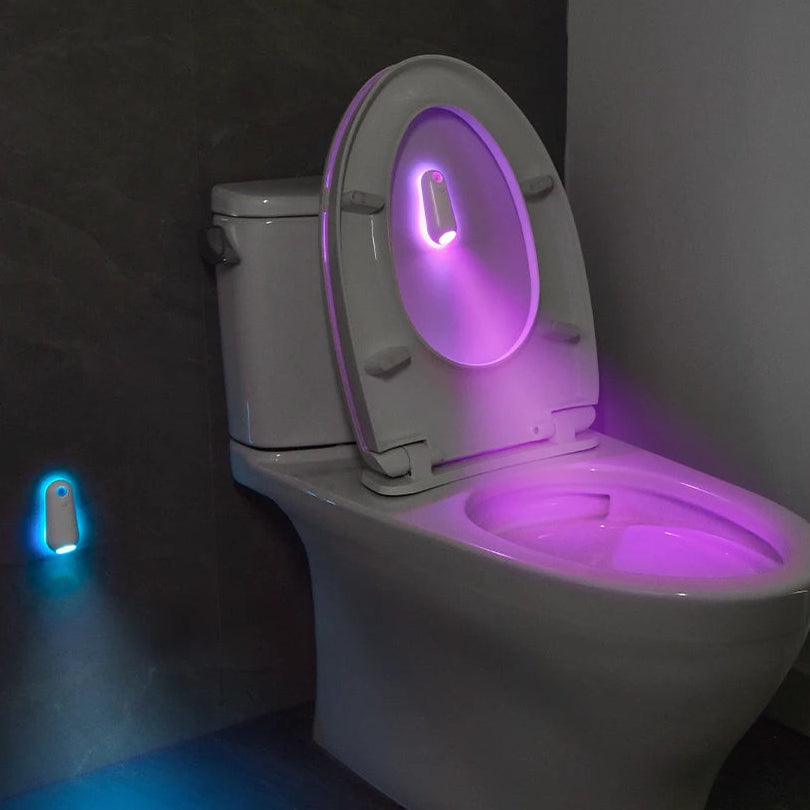 Toilet with a glowing seat in a dark bathroom, showing color-changing options on the side.