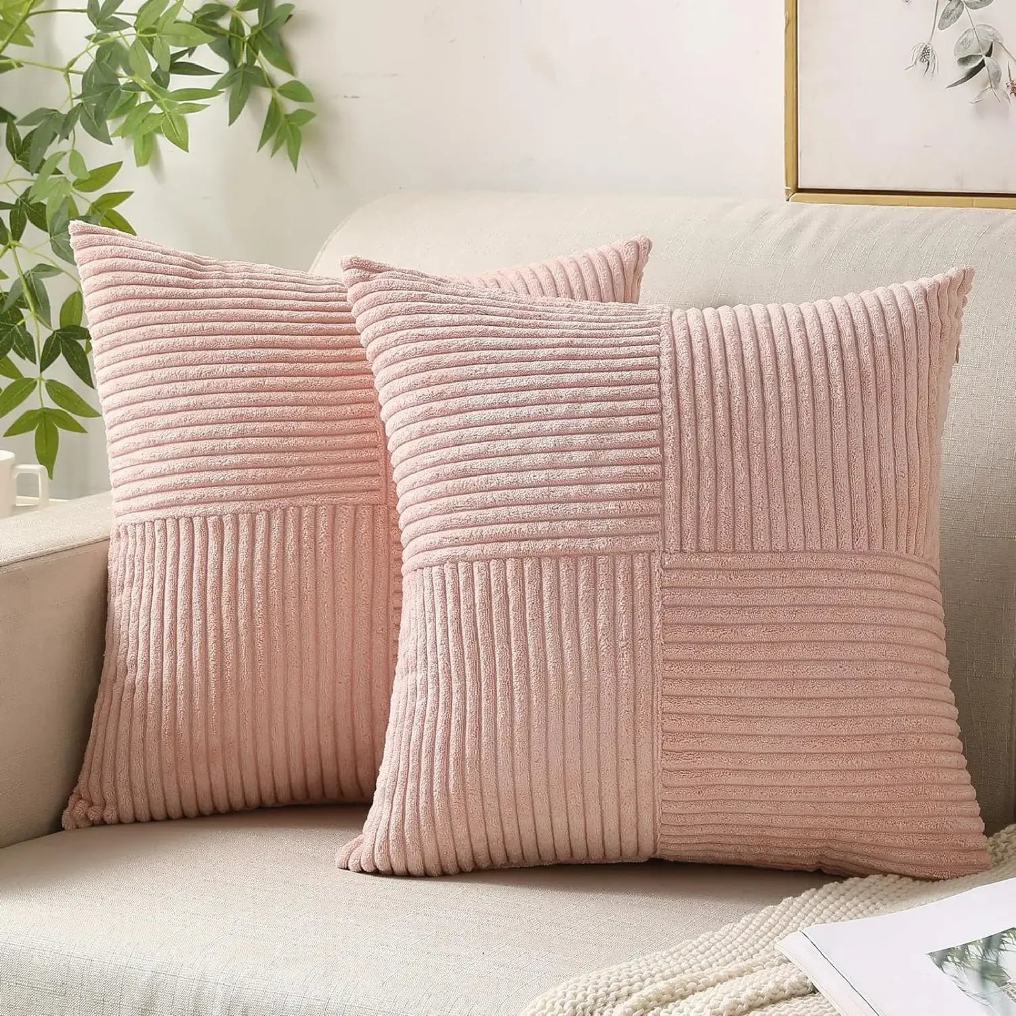 Two pink textured pillows on a sofa with a plant in the background