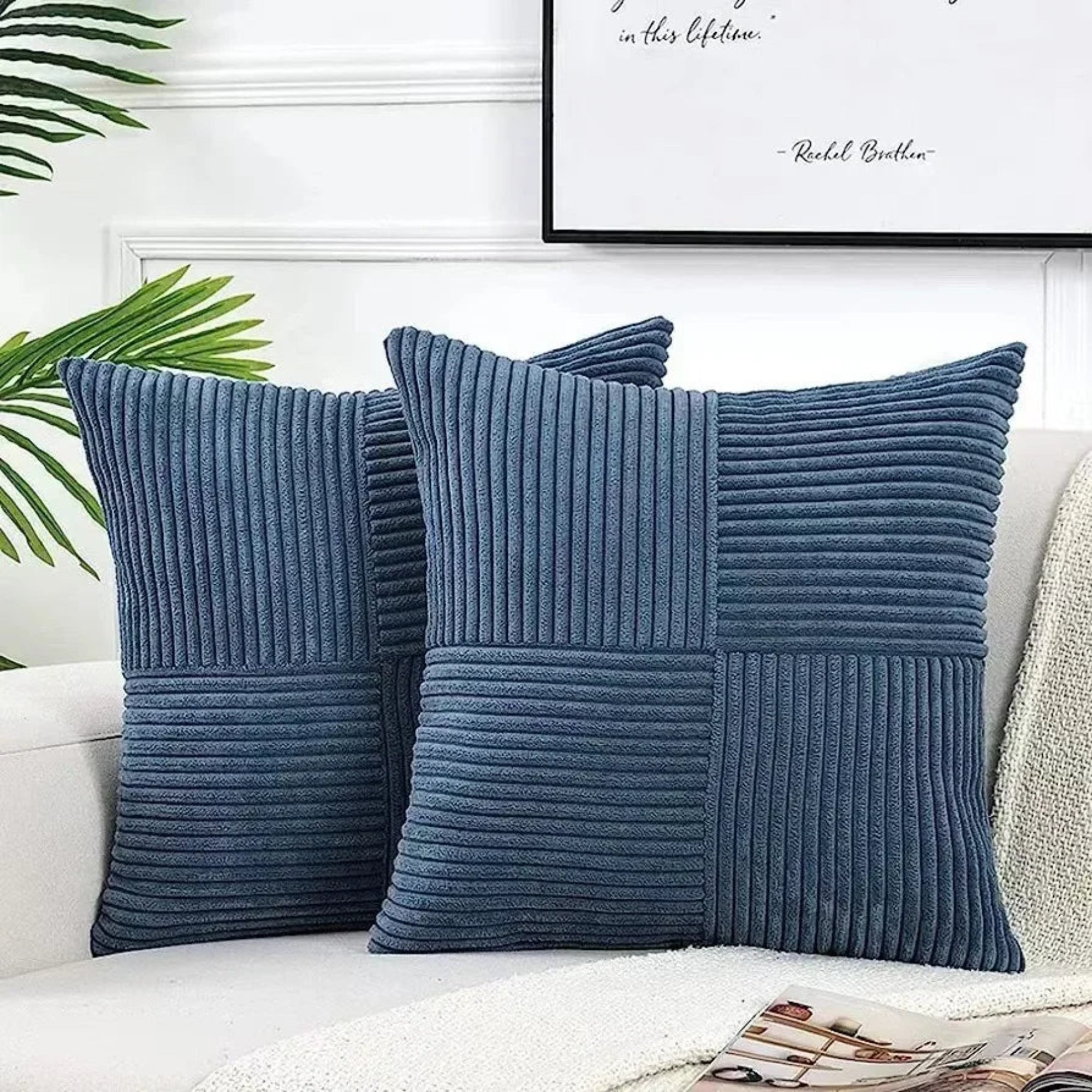 Two blue textured pillows on a white couch with a framed quote in the background.