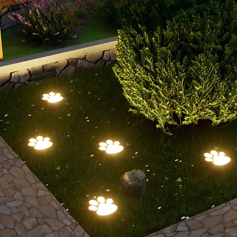 Decorative paw print lights on a garden pond at night