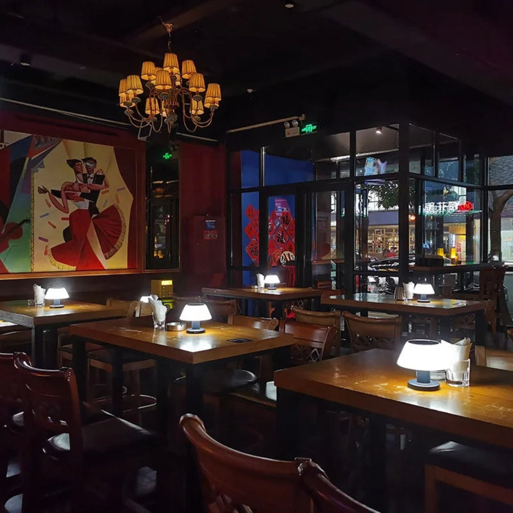 Dining area with tables, chairs, and a chandelier in a restaurant setting.