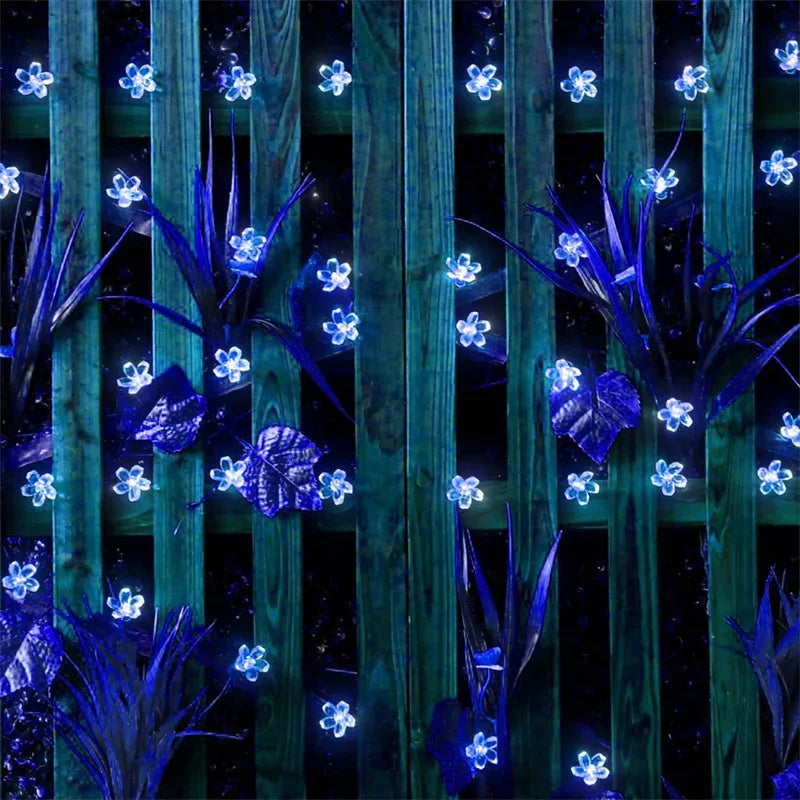 Decorative string lights shaped like flowers on a wooden fence at night.