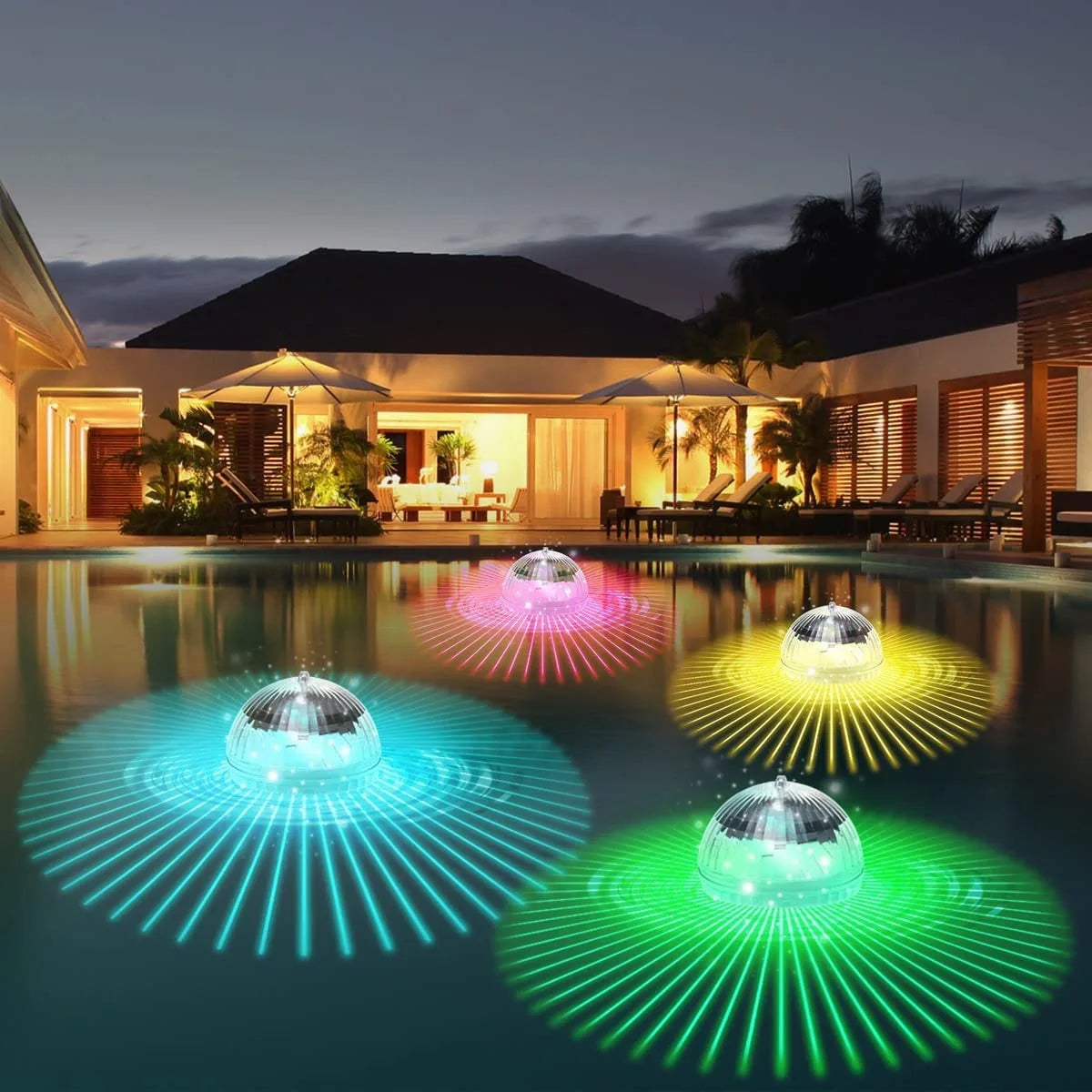 Colorful disco ball lights floating in a pool at night with a house in the background.