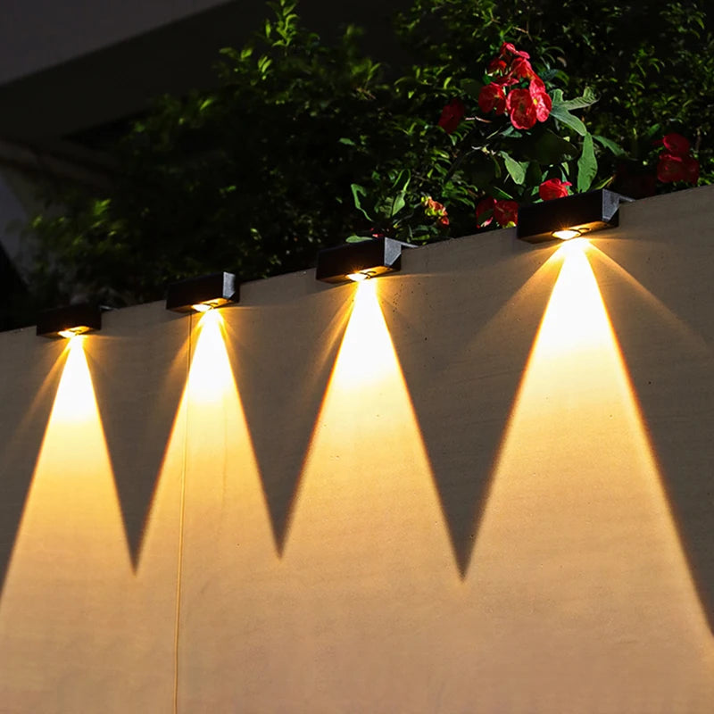 Solar-powered outdoor lights on a wall with plants in the background