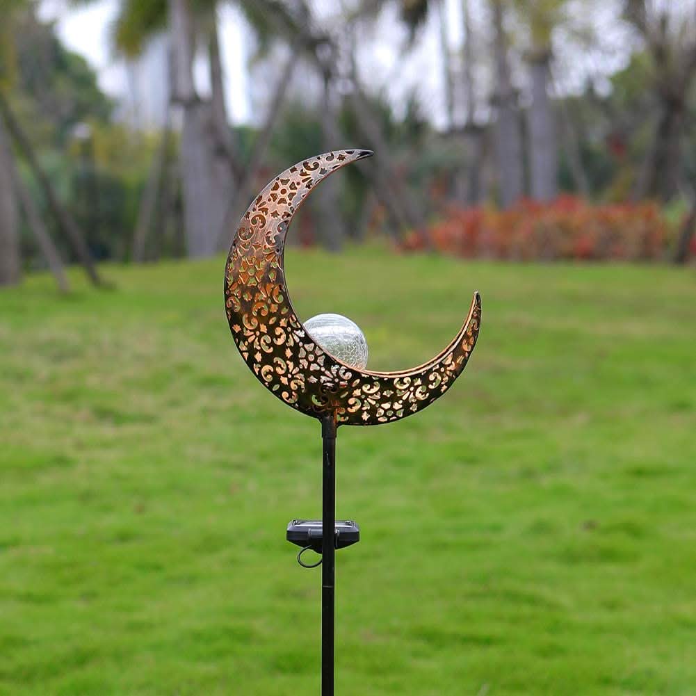 Decorative garden stake with a crescent moon design on a grassy background