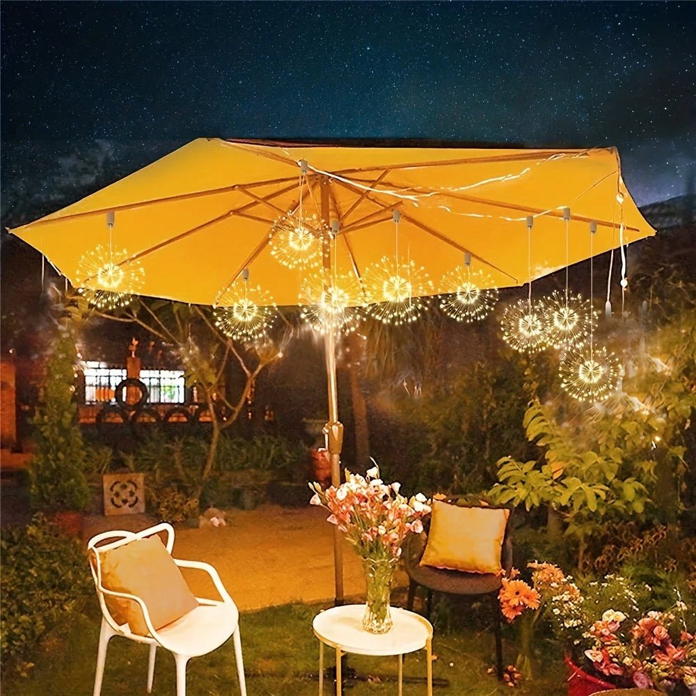 Yellow patio umbrella with string lights in a garden setting at night.