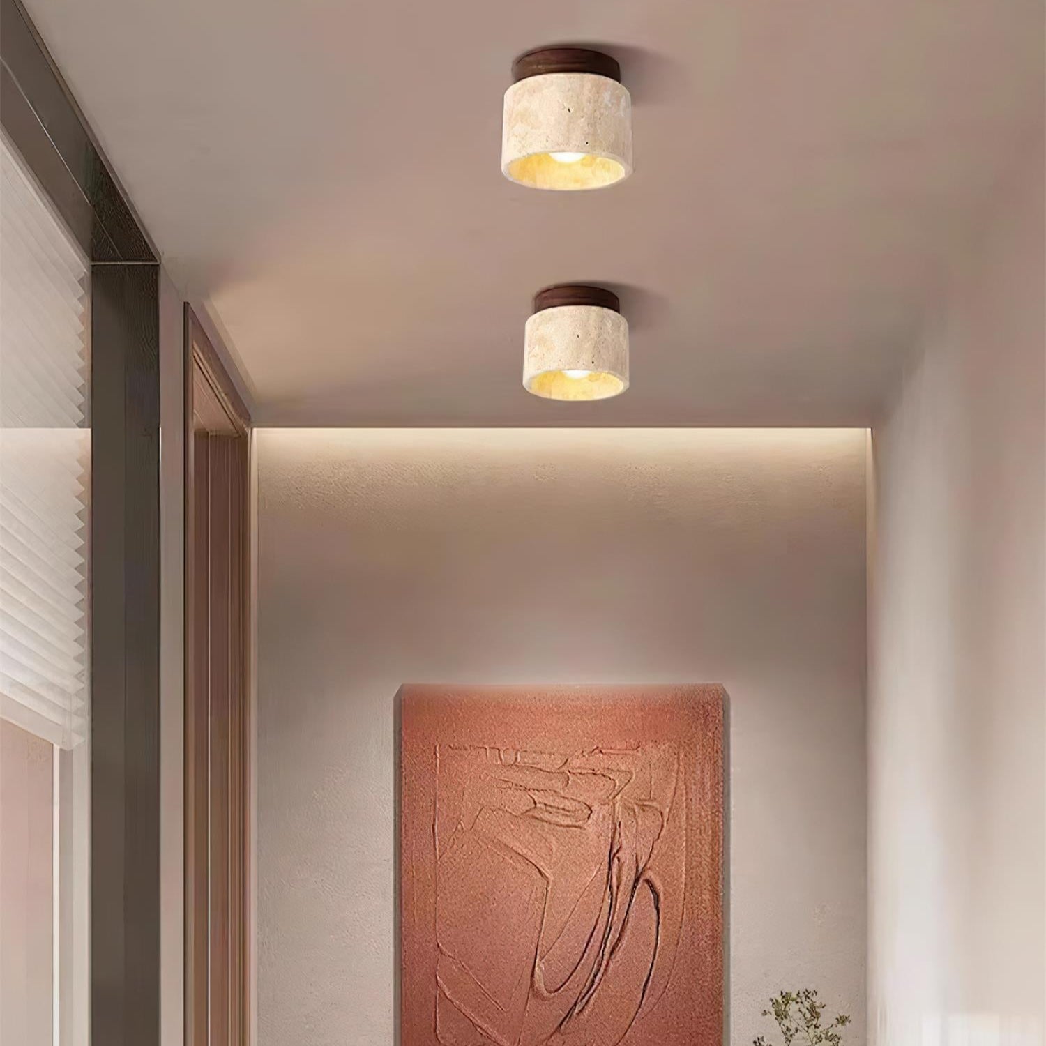 Modern ceiling lights in a room with a decorative wall piece and plant.