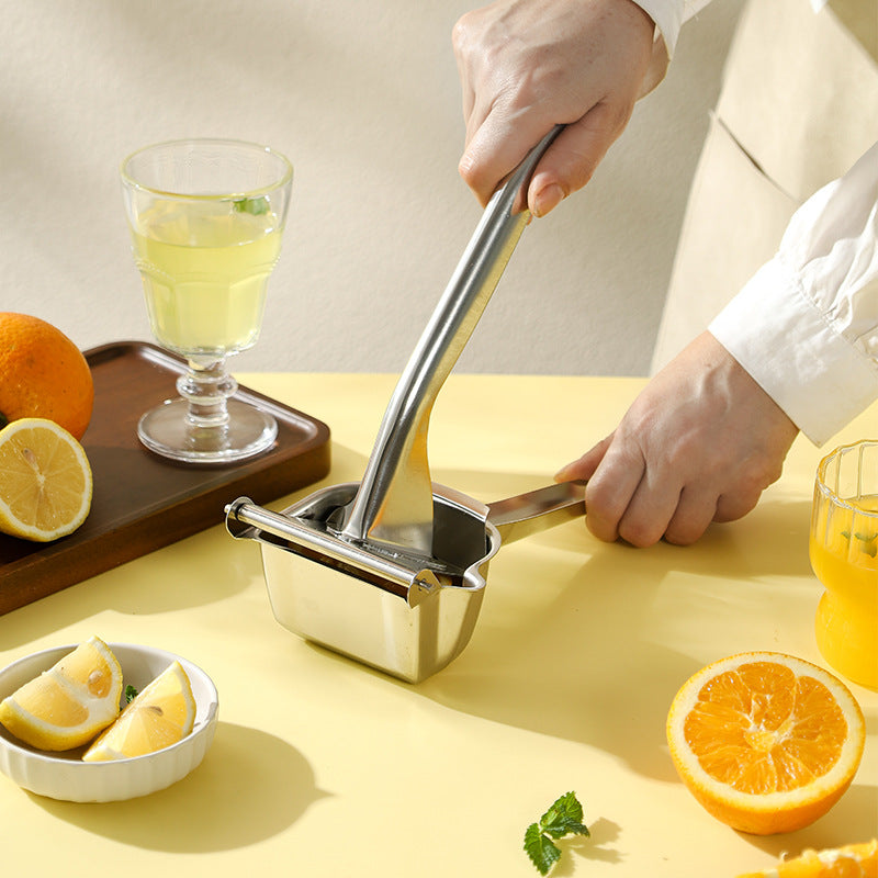 Person using a manual juicer with lemons and oranges on a yellow surface