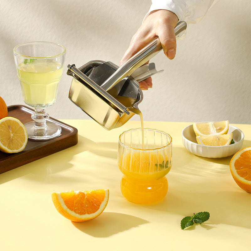 Hand using a manual juicer to extract juice from oranges on a yellow surface.