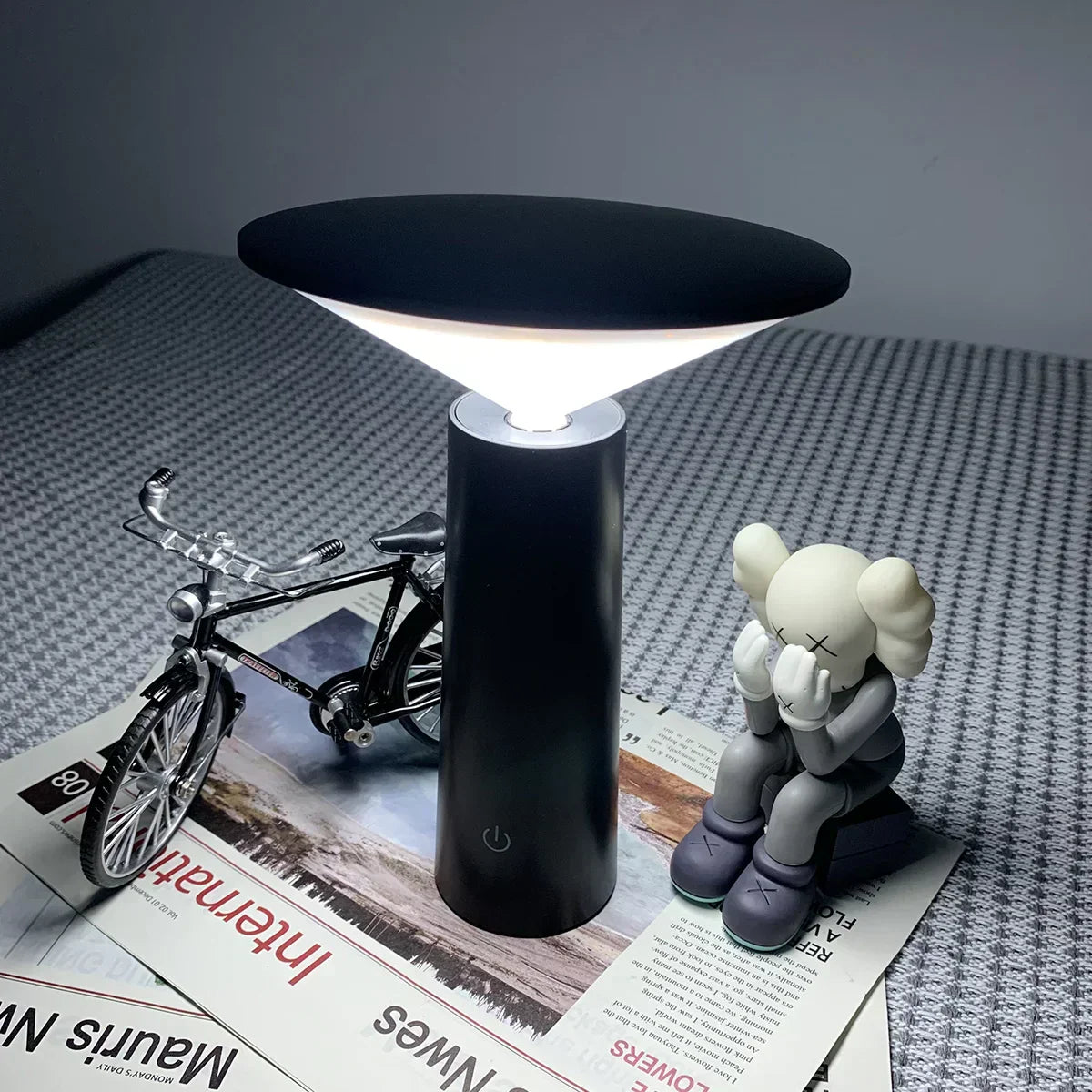 Black table lamp on a surface with a toy and bicycle model