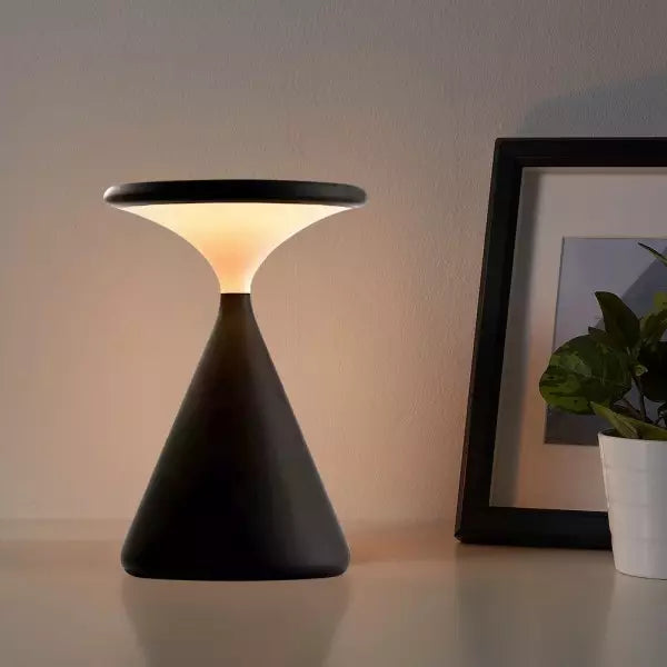 Modern black table lamp on a surface with a blurred background