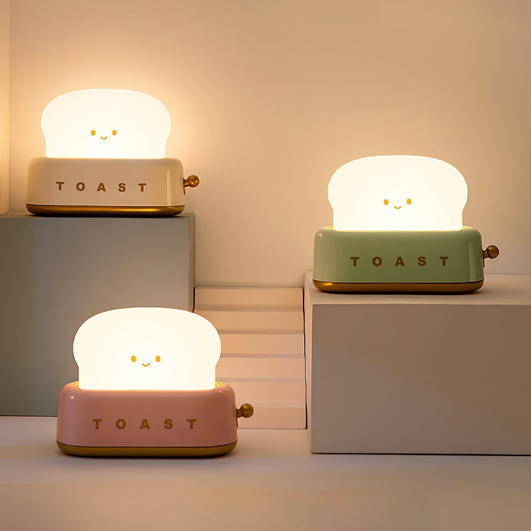 Three cute toast-shaped night lights in different colors on a neutral background
