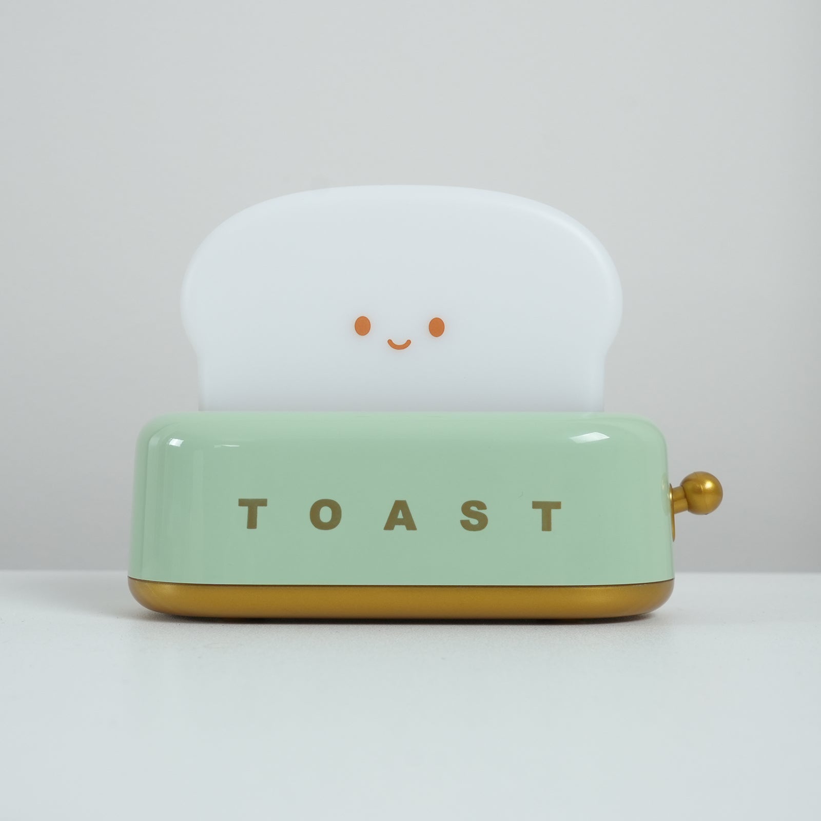 Light green toaster with a smiling white bread slice on a light gray background