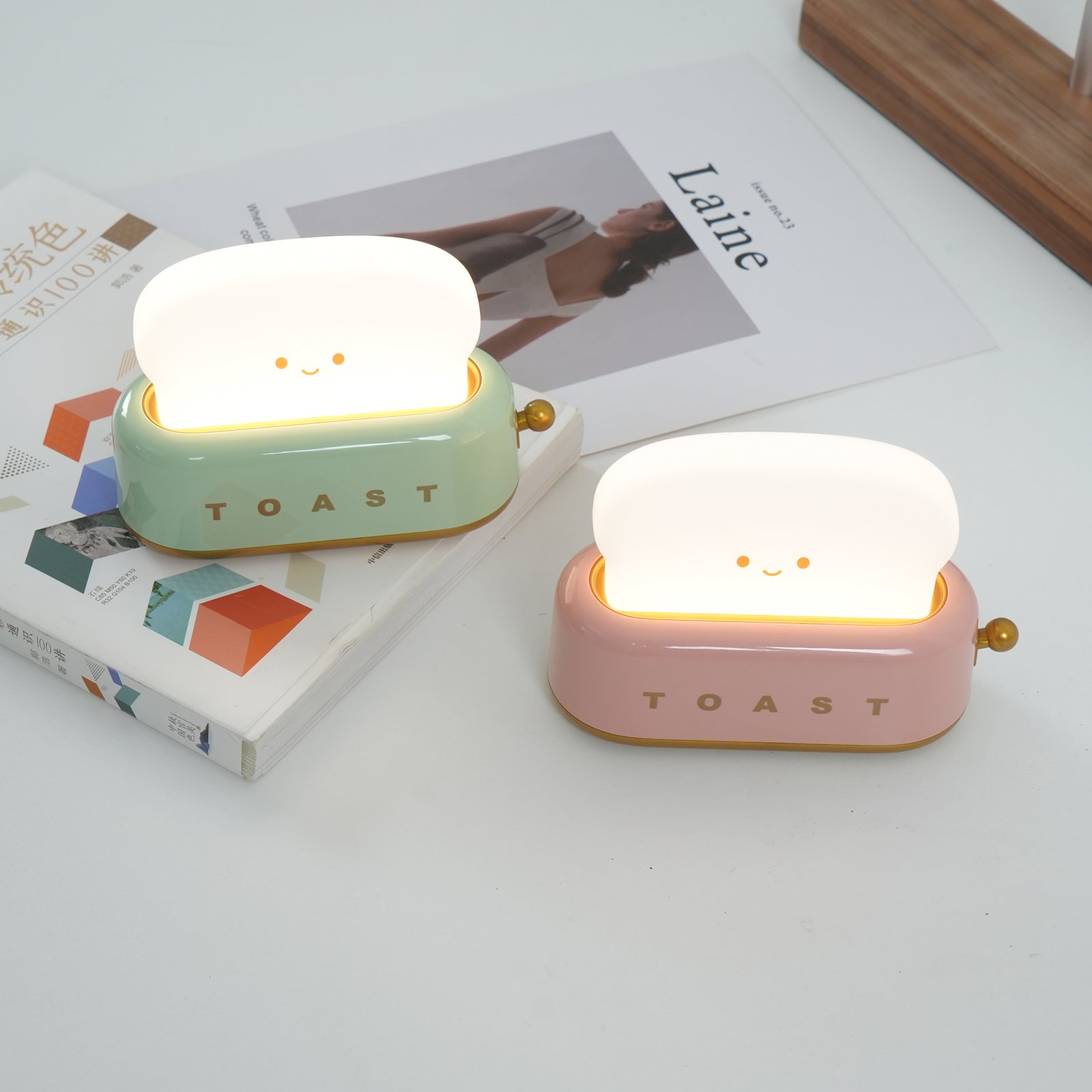 Two cute toast-shaped night lights on a surface with a magazine underneath.
