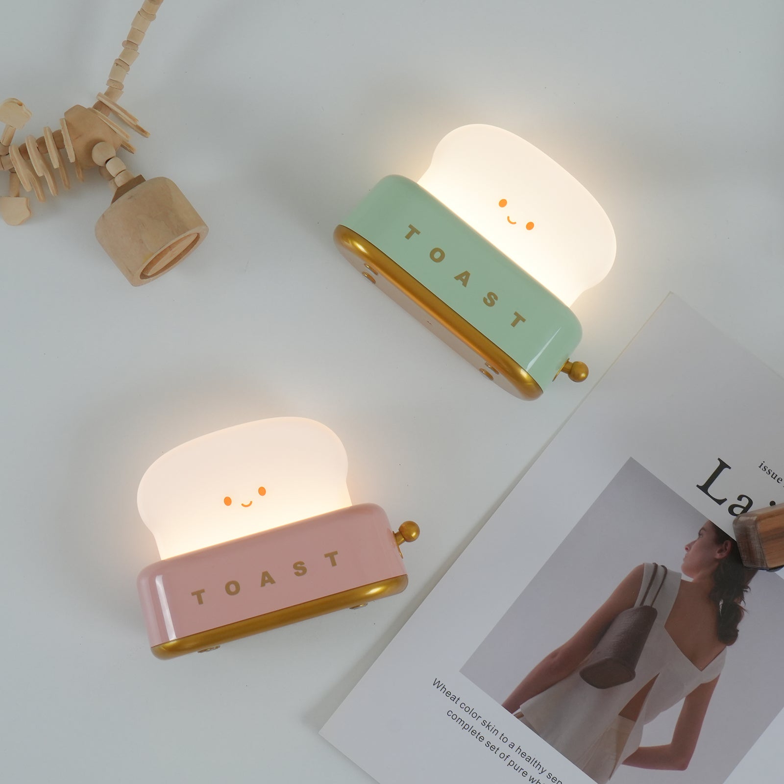 Two cute toaster-shaped night lights, one pink and one green, on a light surface.
