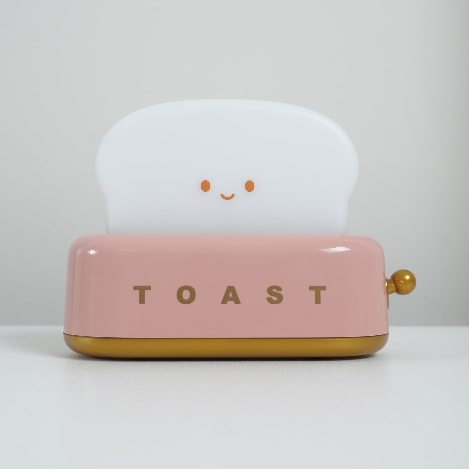 Pink toaster with a smiling face on a white background