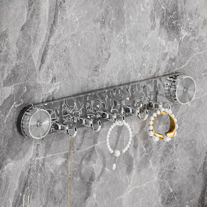 Metal jewelry holder with hooks on a marble wall