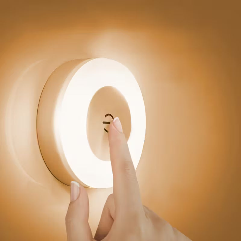 Hand pressing a round light switch on an orange wall