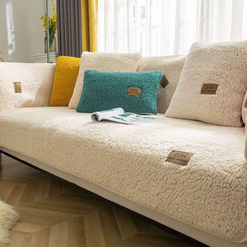 Beige sofa with decorative pillows and a magazine on a wooden floor.