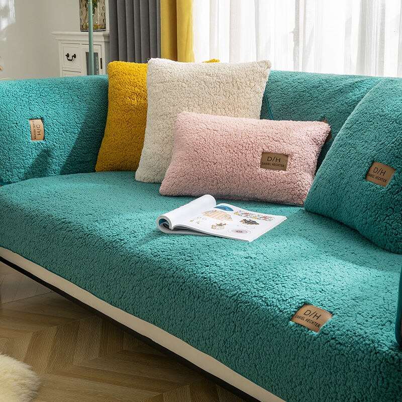 Teal sofa with colorful pillows and a magazine on a wooden floor.