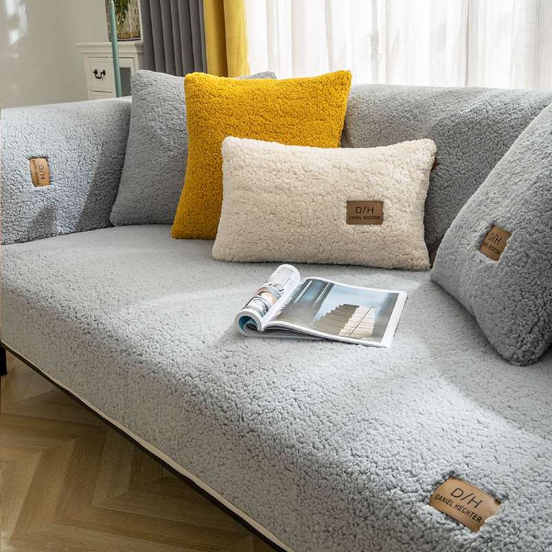 Gray sofa with plush cushions and a magazine on a wooden floor.