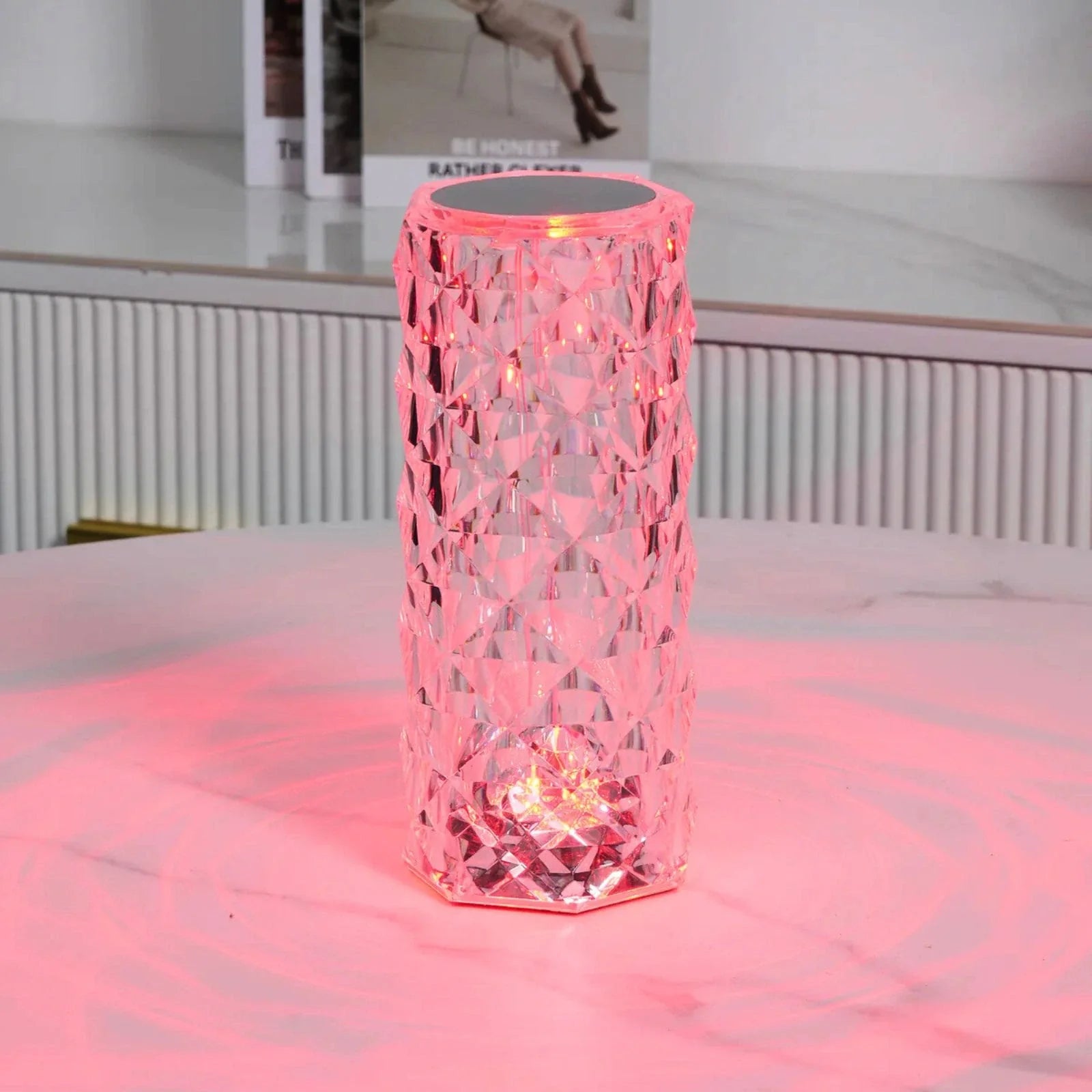 Pink textured cylindrical lamp on a white surface with a blurred background