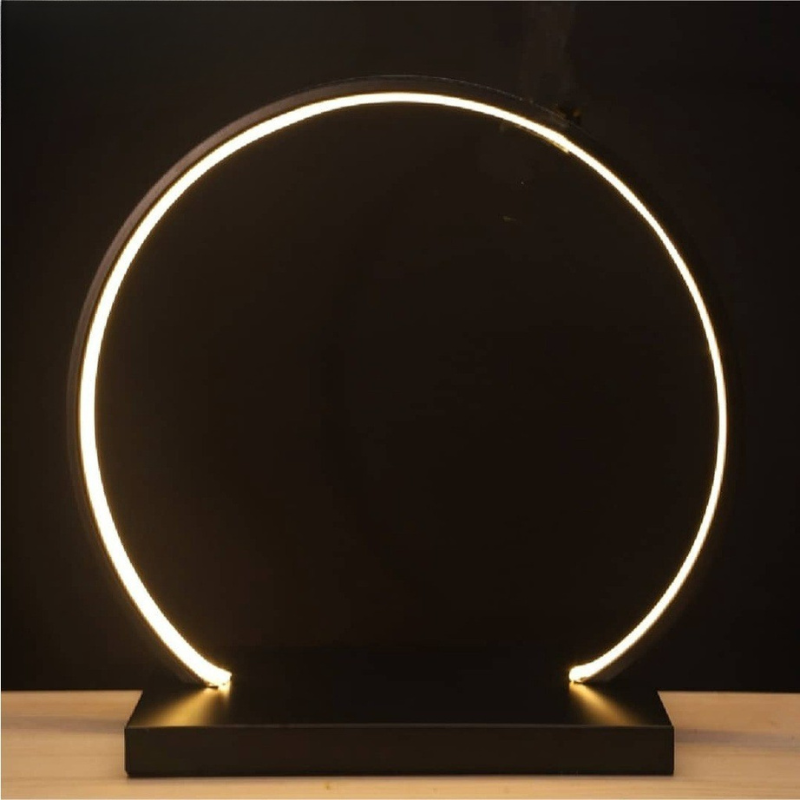 Modern table lamp with circular design and glowing light on a dark background