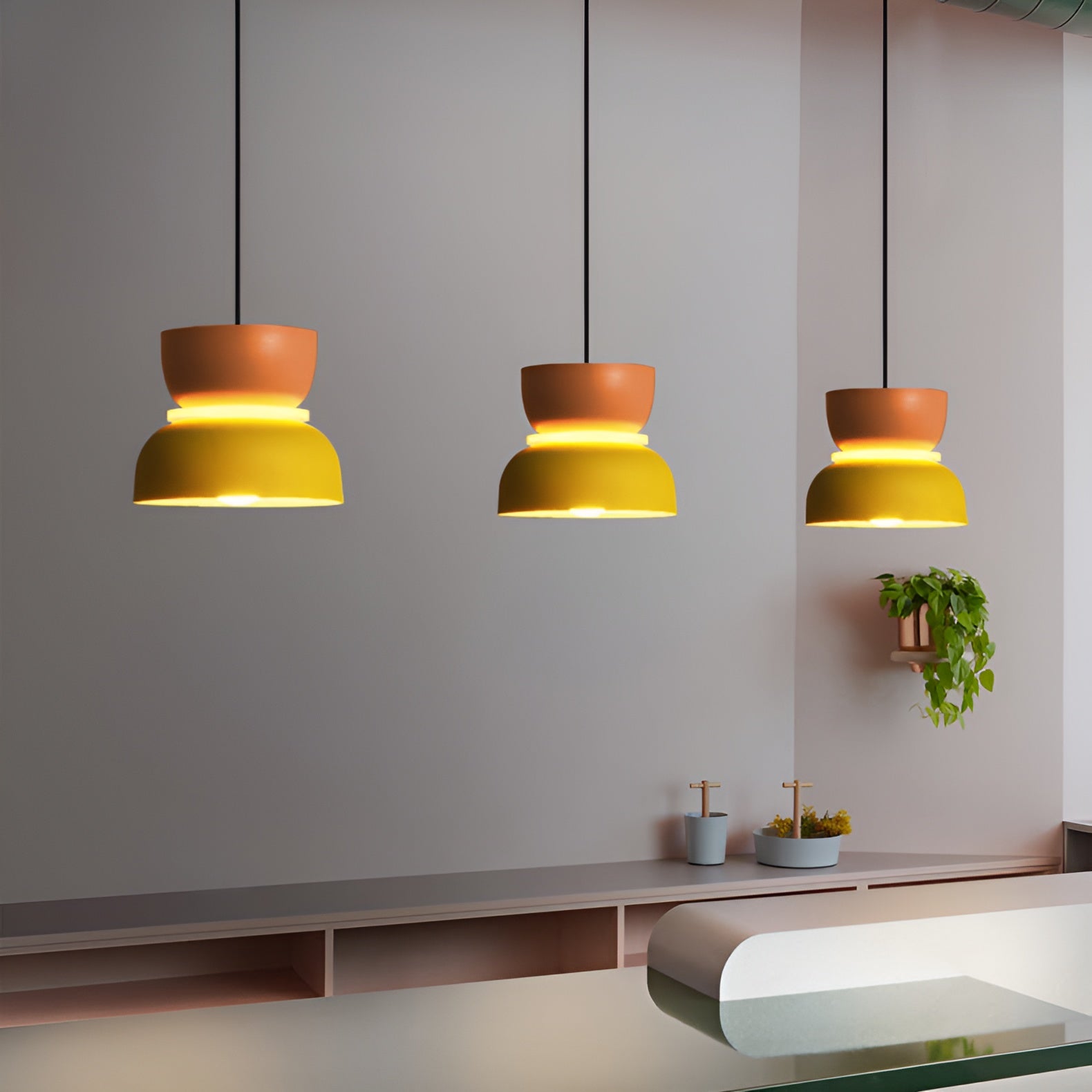 Three pendant lights hanging above a kitchen counter with a neutral background