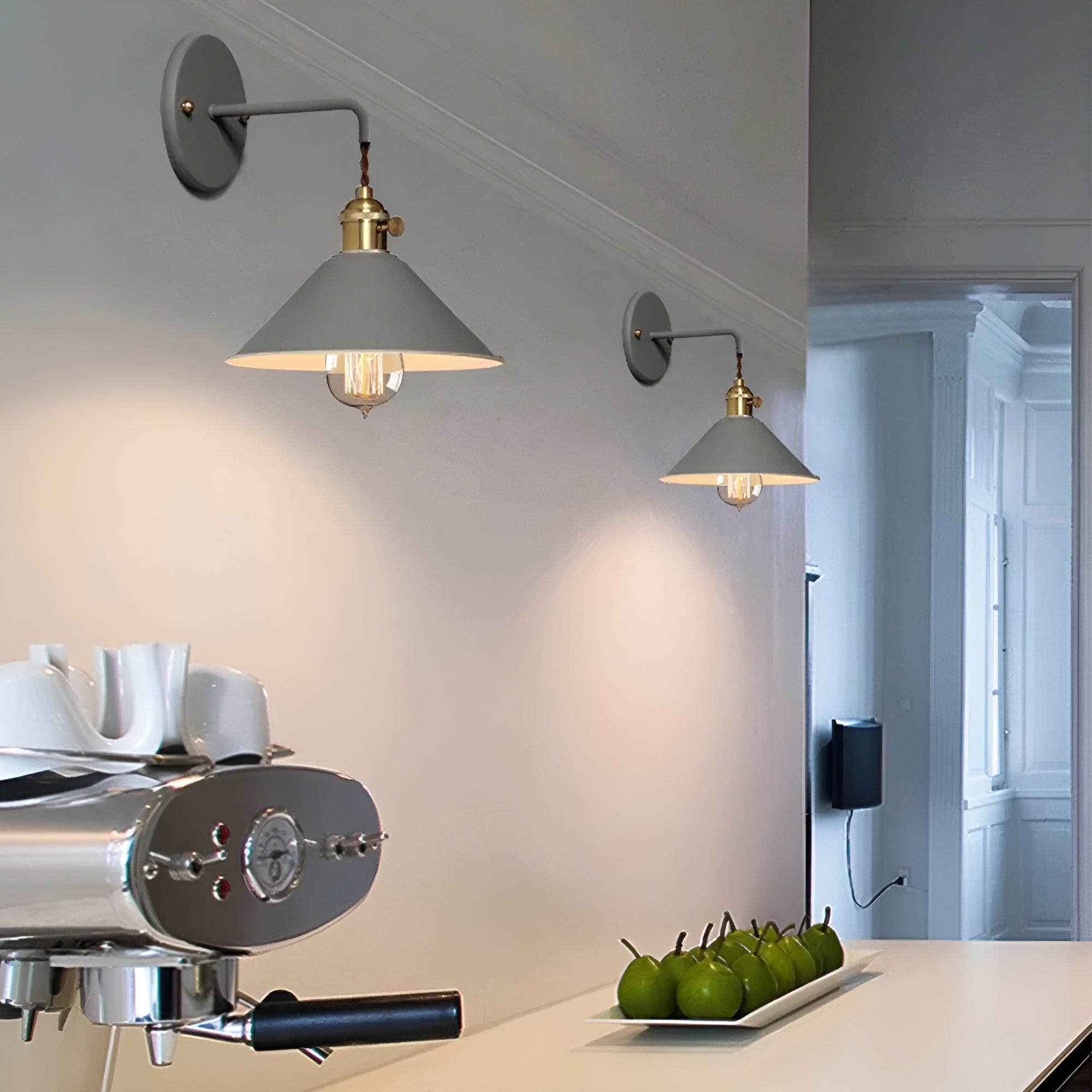 Modern kitchen with coffee machine, green apples on a plate, and wall lights.