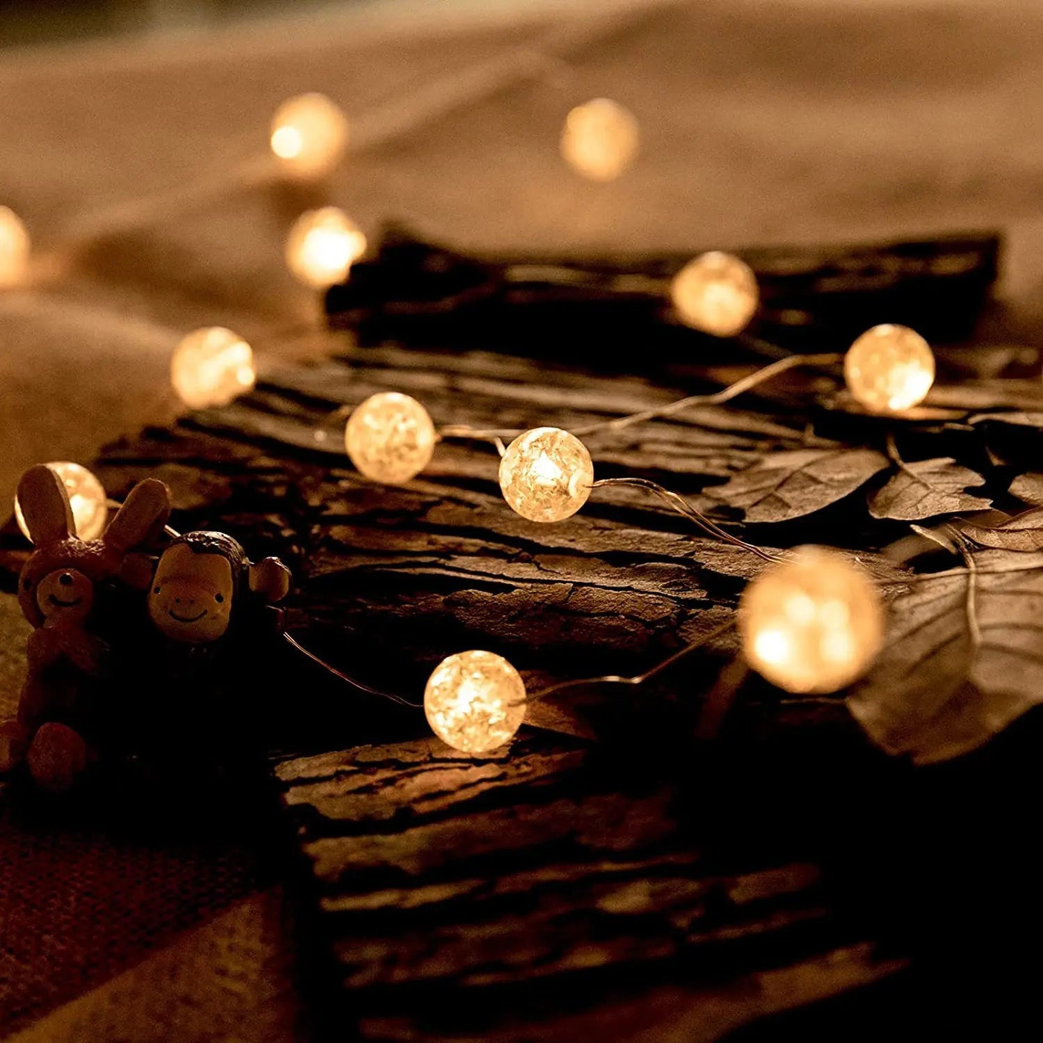 String lights with glowing bulbs on a textured surface with small figurines.