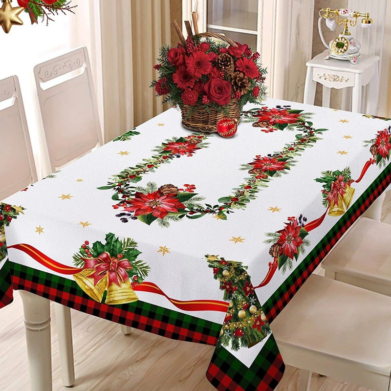 Christmas-themed tablecloth with poinsettias, ribbons, and bells on a dining table.