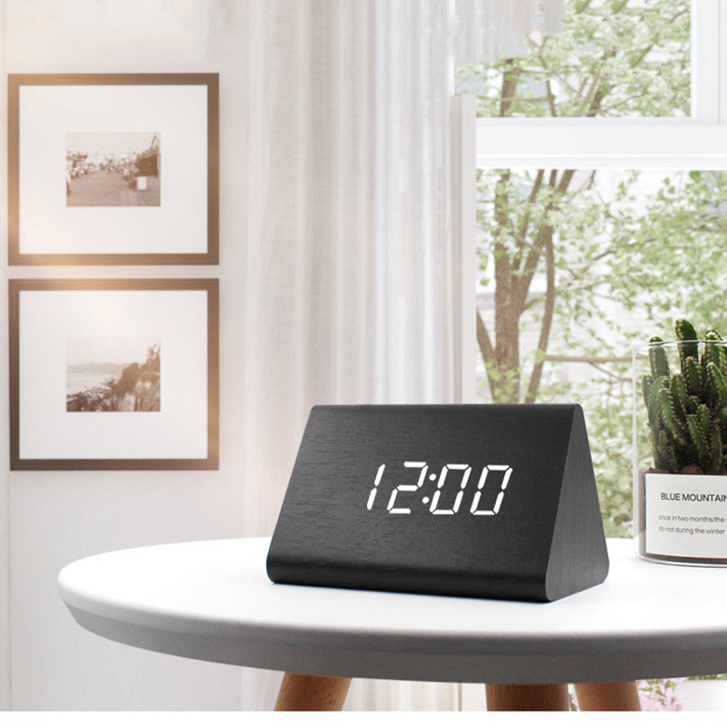Black digital clock on a white table with a blurred indoor background