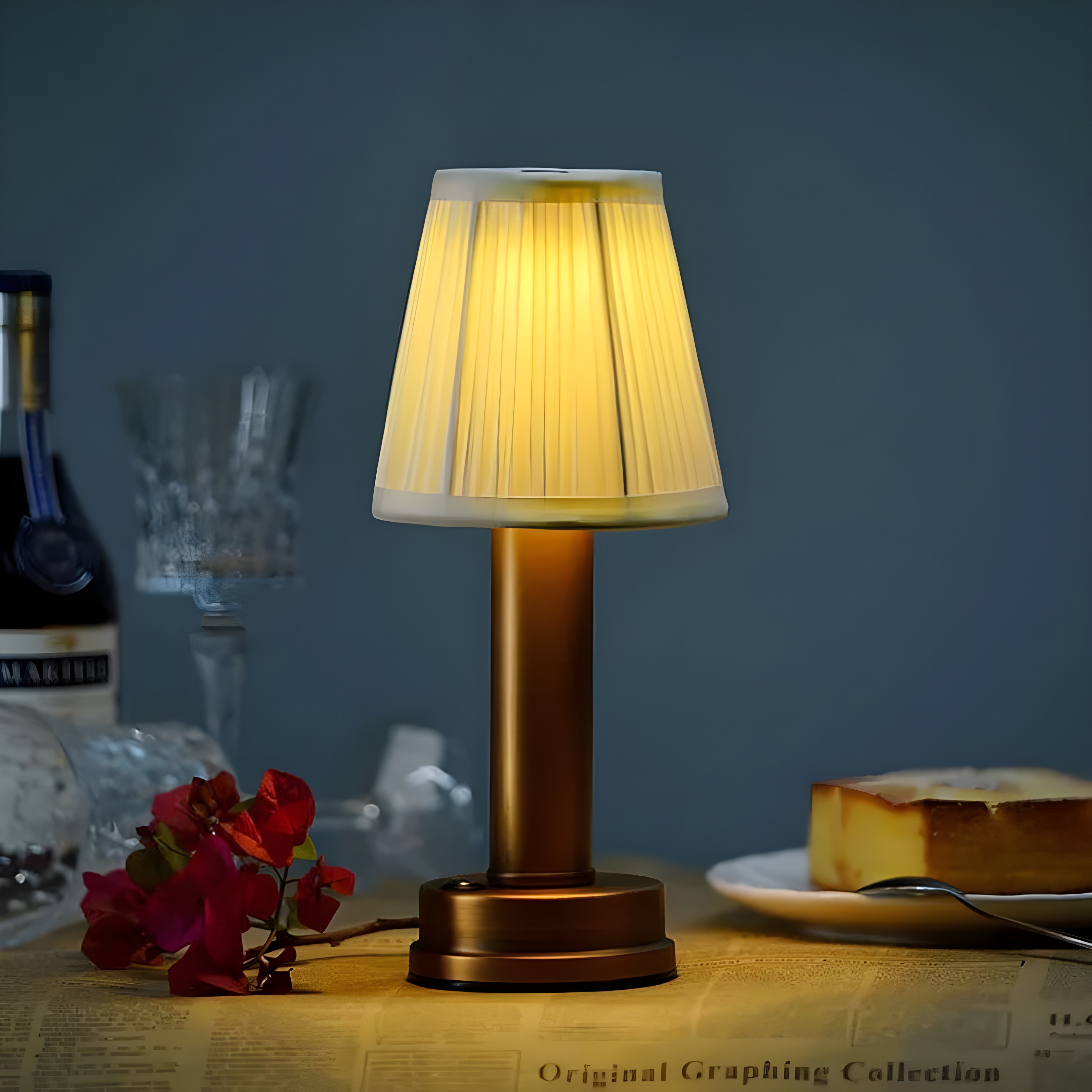 Table lamp on a table with a bottle, glass, and cake in the background