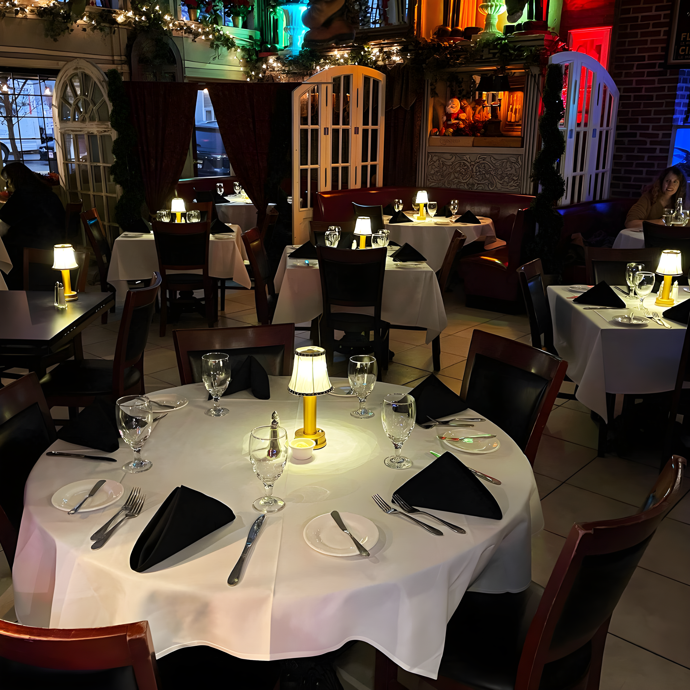 Dining area with tables set for meals, including wine glasses and cutlery, in a restaurant setting.