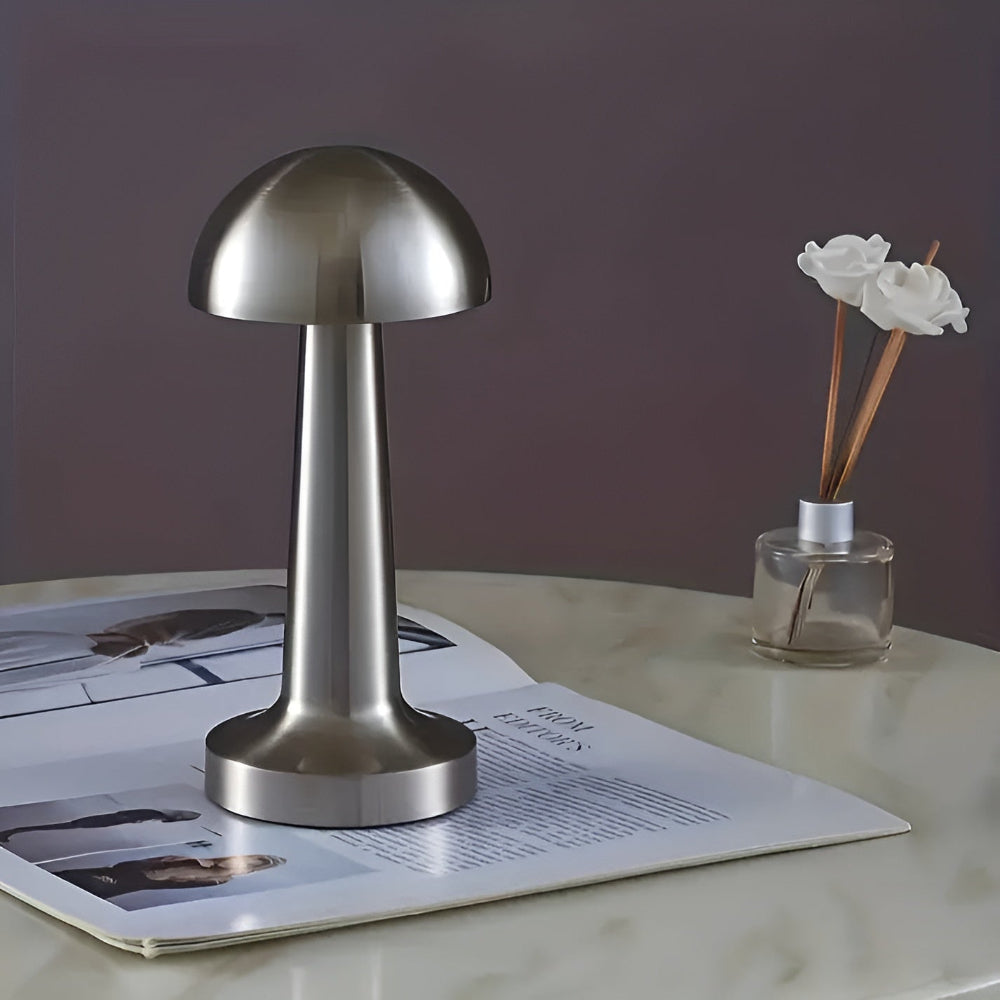 Silver mushroom-shaped lamp on a magazine with a diffuser bottle in the background.