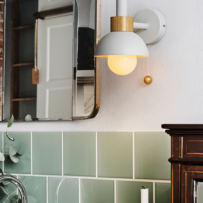 Wall-mounted light fixture above a mirror in a bathroom with green tiles.