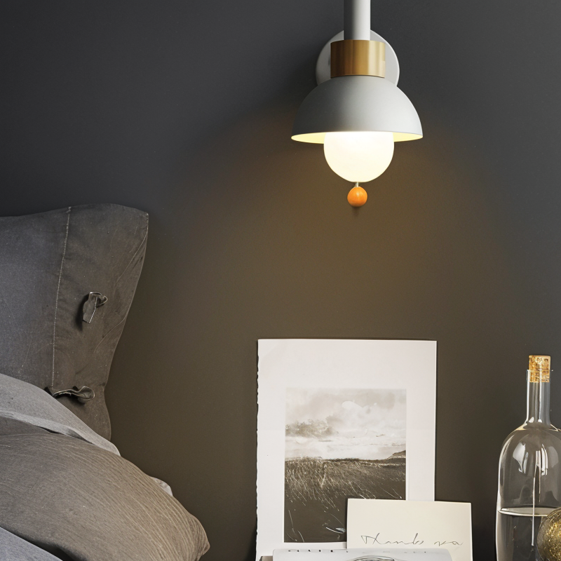 Pendant light fixture on a dark wall with a photograph and bottle below.