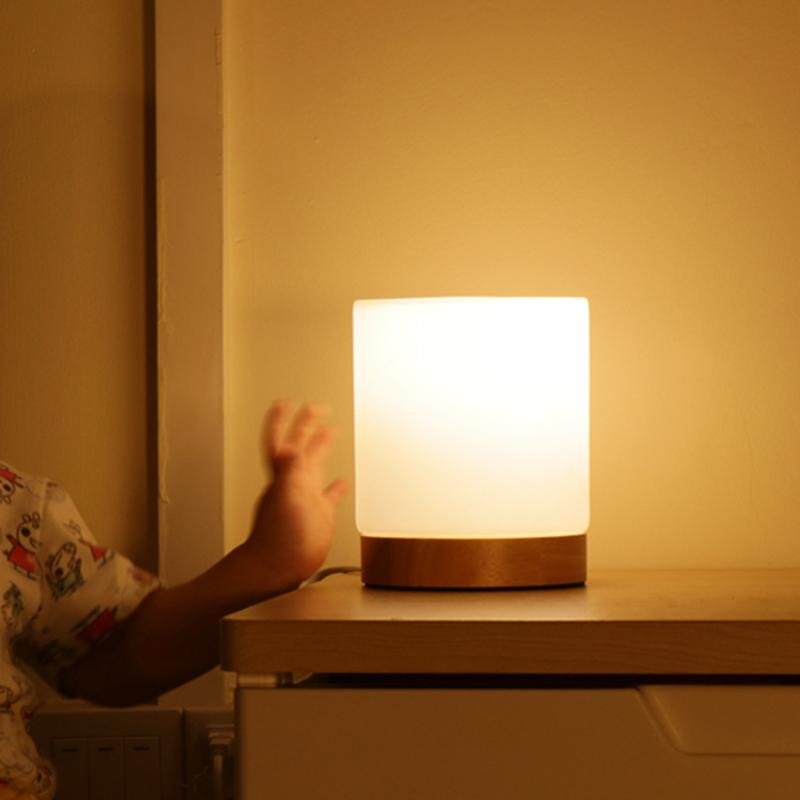 Person reaching out to a glowing night light on a surface with a warm, soft glow.